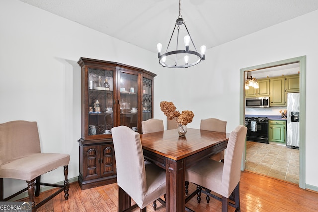 dining space with light wood-style flooring, baseboards, and a chandelier