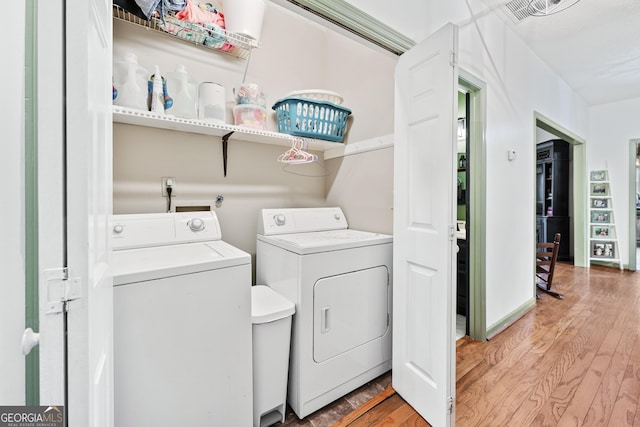 laundry area featuring visible vents, baseboards, washing machine and dryer, light wood-type flooring, and laundry area