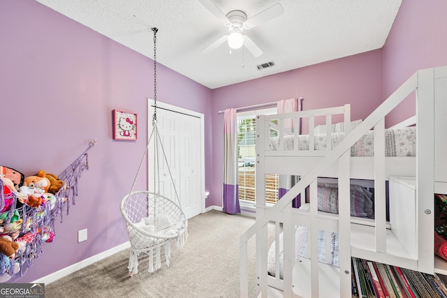 carpeted bedroom featuring visible vents, baseboards, a textured ceiling, and a closet