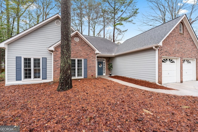 traditional-style house featuring a garage, brick siding, driveway, and roof with shingles