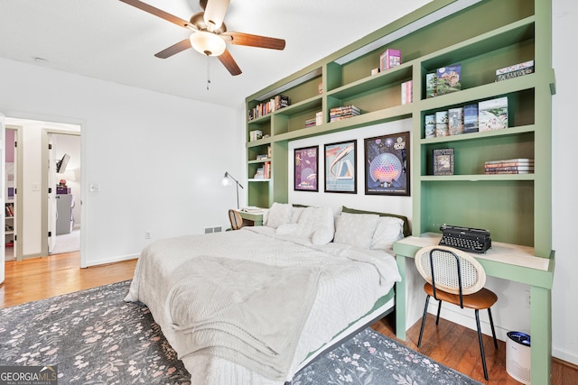 bedroom with baseboards, built in study area, a ceiling fan, and wood finished floors