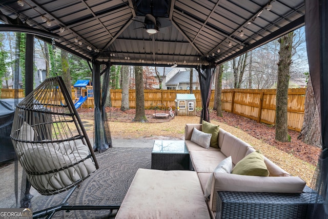 view of patio / terrace with a ceiling fan, an outdoor living space, a fenced backyard, a playground, and a gazebo