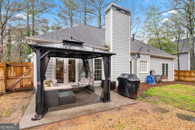 rear view of house with a shingled roof, fence, a gazebo, a chimney, and a patio