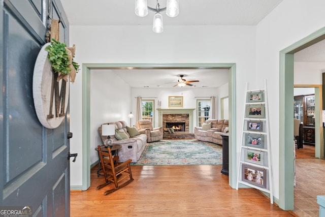 foyer with a fireplace, light wood-type flooring, and a ceiling fan