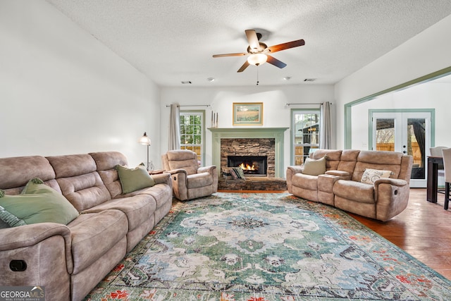 living area with french doors, a healthy amount of sunlight, wood finished floors, and a fireplace