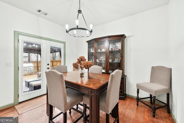 dining space featuring visible vents, french doors, light wood-type flooring, and an inviting chandelier