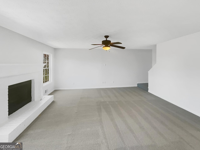 unfurnished living room with a ceiling fan, visible vents, carpet, baseboards, and a brick fireplace