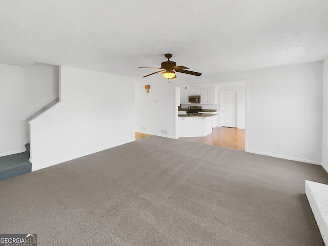 unfurnished living room with light colored carpet, a textured ceiling, and ceiling fan