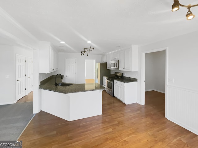 kitchen featuring a sink, wood finished floors, appliances with stainless steel finishes, and white cabinets