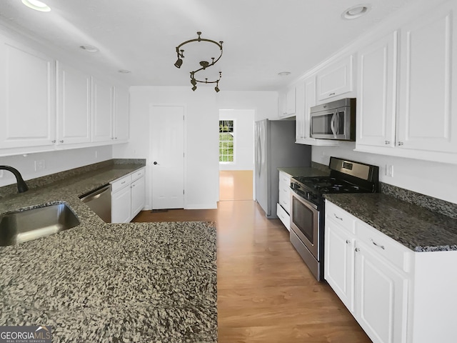 kitchen featuring a sink, dark stone counters, appliances with stainless steel finishes, and white cabinetry