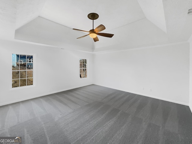 spare room with dark carpet, baseboards, a raised ceiling, and ceiling fan