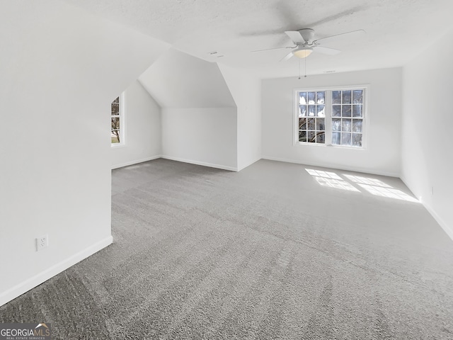 additional living space with baseboards, lofted ceiling, ceiling fan, a textured ceiling, and carpet flooring