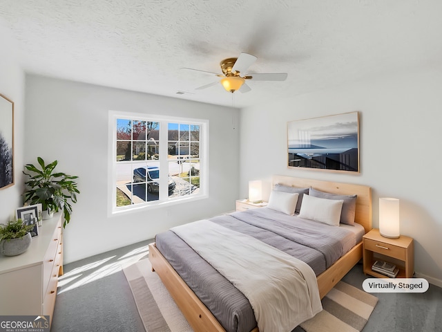 carpeted bedroom featuring visible vents, a textured ceiling, and a ceiling fan