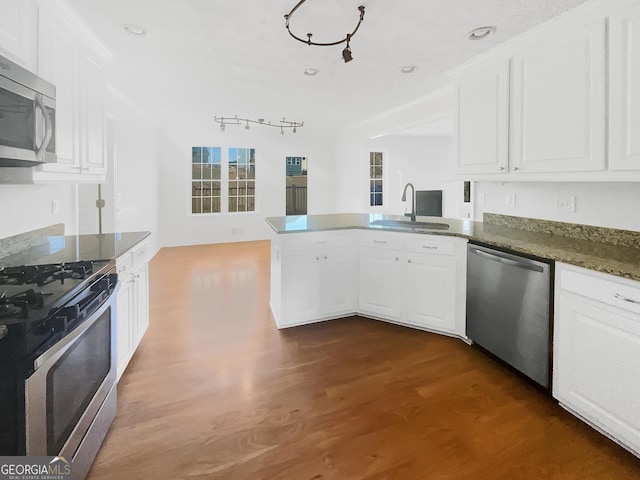 kitchen featuring a sink, a peninsula, white cabinets, and stainless steel appliances