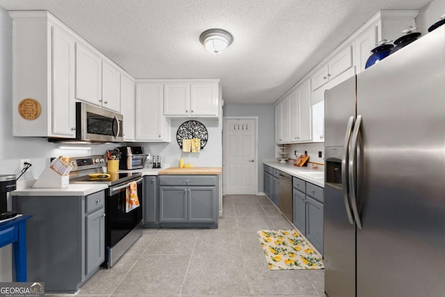 kitchen with stainless steel appliances, light countertops, gray cabinetry, and white cabinetry