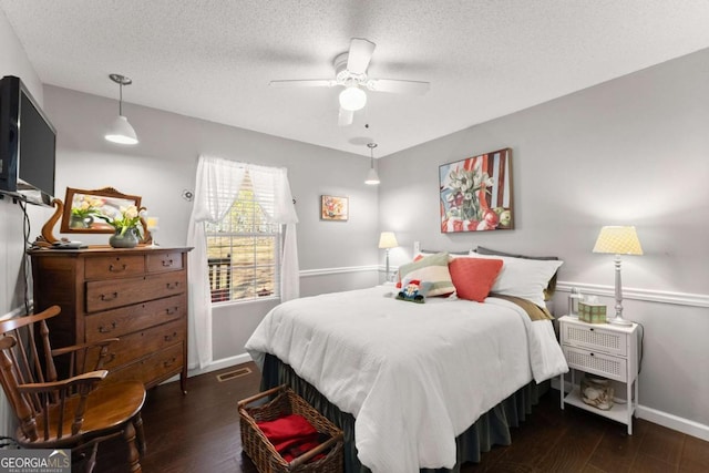 bedroom featuring a textured ceiling, ceiling fan, wood finished floors, visible vents, and baseboards