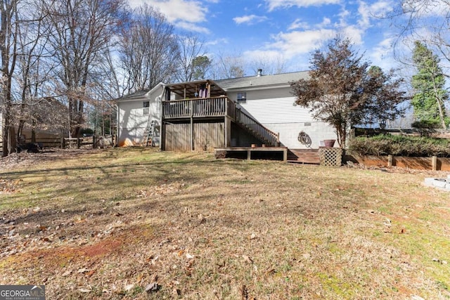 rear view of house with stairway, a wooden deck, a lawn, and fence