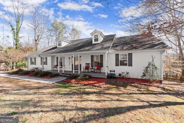 cape cod-style house featuring covered porch and a front lawn