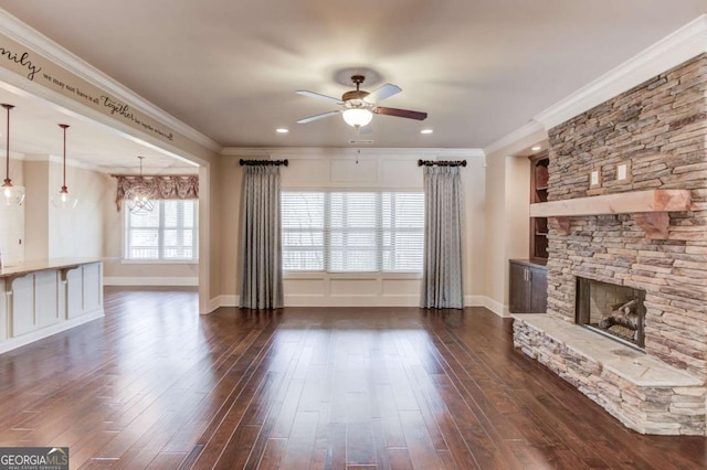 unfurnished living room with ceiling fan, ornamental molding, dark wood-style flooring, and a fireplace