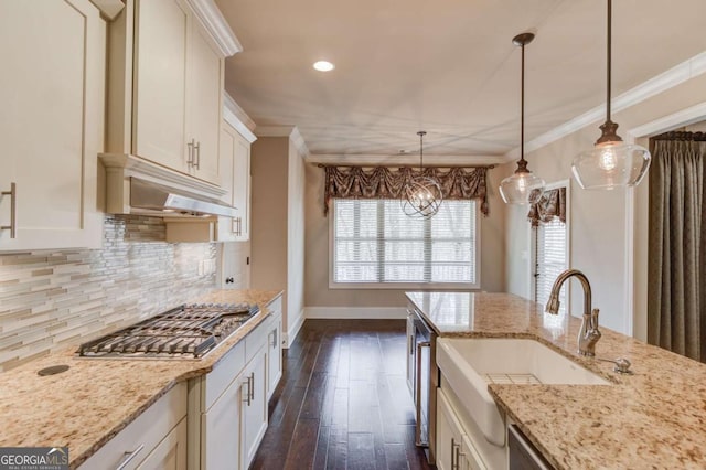 kitchen with stainless steel gas cooktop, decorative backsplash, a sink, and ornamental molding