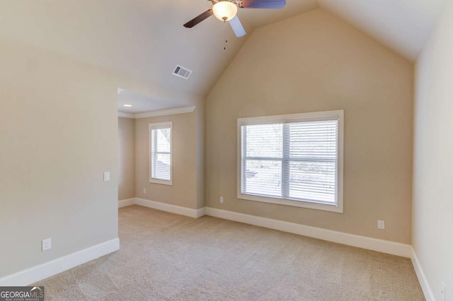 empty room featuring baseboards, visible vents, a ceiling fan, vaulted ceiling, and carpet flooring