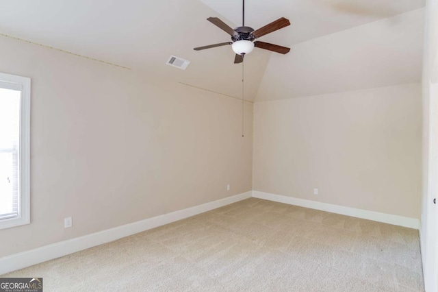 unfurnished room featuring carpet, visible vents, vaulted ceiling, and baseboards