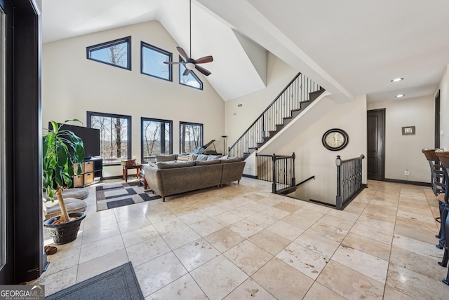 living room featuring high vaulted ceiling, plenty of natural light, stairway, and a ceiling fan