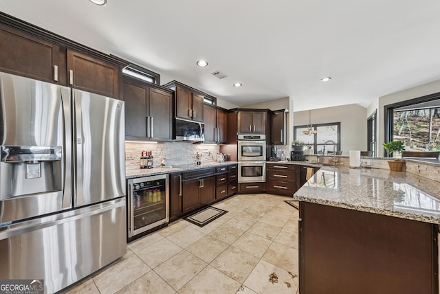 kitchen featuring wine cooler, stainless steel appliances, decorative backsplash, dark brown cabinets, and a peninsula