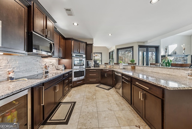 kitchen with stainless steel appliances, tasteful backsplash, visible vents, a sink, and beverage cooler