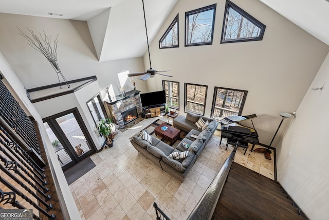 living room featuring ceiling fan, high vaulted ceiling, a fireplace, and visible vents