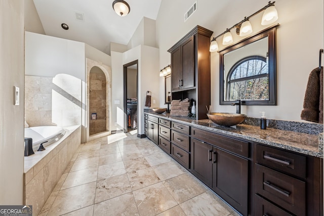 bathroom with double vanity, visible vents, a sink, tiled shower, and a bath