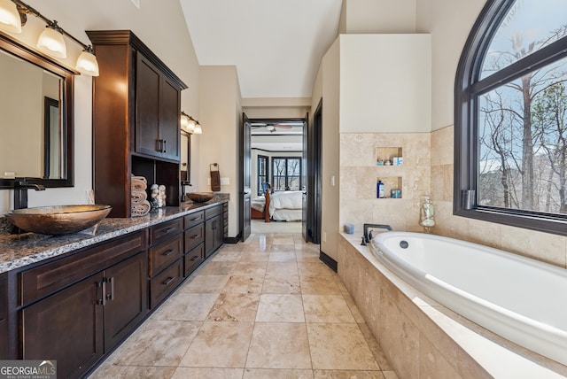 bathroom with ensuite bathroom, double vanity, a sink, and a bath