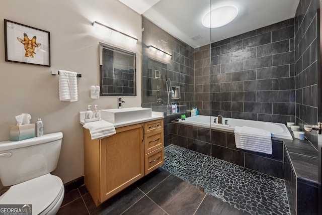 bathroom featuring tile patterned flooring, vanity, toilet, and tiled tub