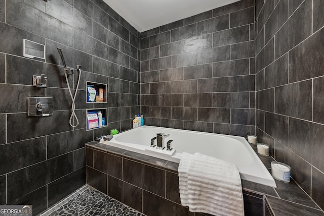 full bath featuring a garden tub, a tile shower, and tile walls