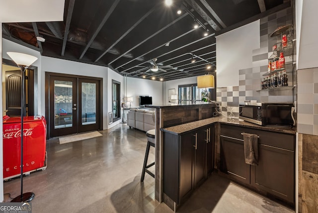 kitchen with a peninsula, concrete floors, stainless steel microwave, and french doors