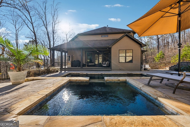 pool with a patio area, fence, and an in ground hot tub