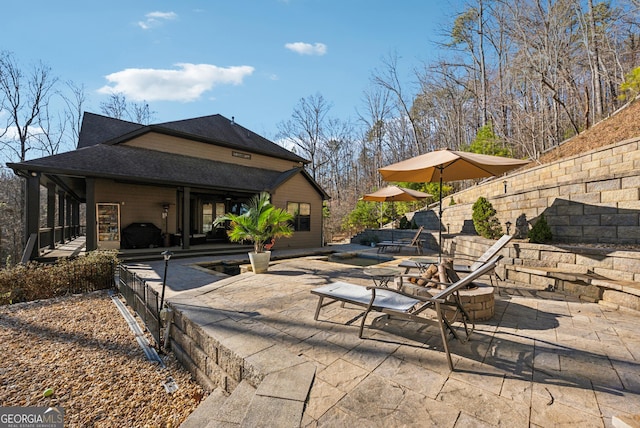 exterior space with a shingled roof and a patio