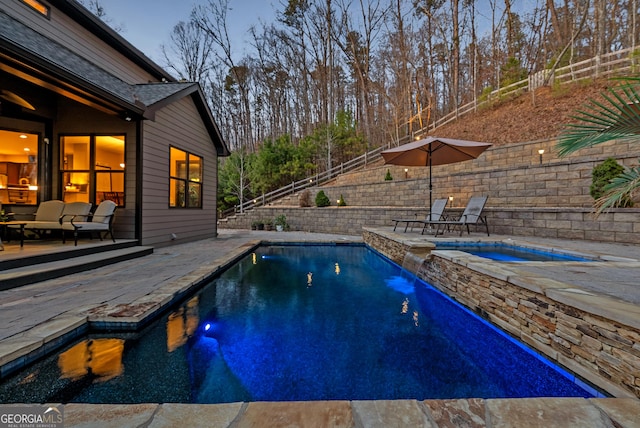 view of swimming pool featuring a pool with connected hot tub, a patio, and fence