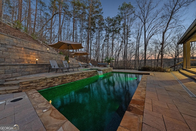 pool at dusk featuring a patio area and a fenced in pool