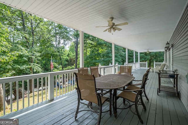 wooden terrace with outdoor dining area and ceiling fan