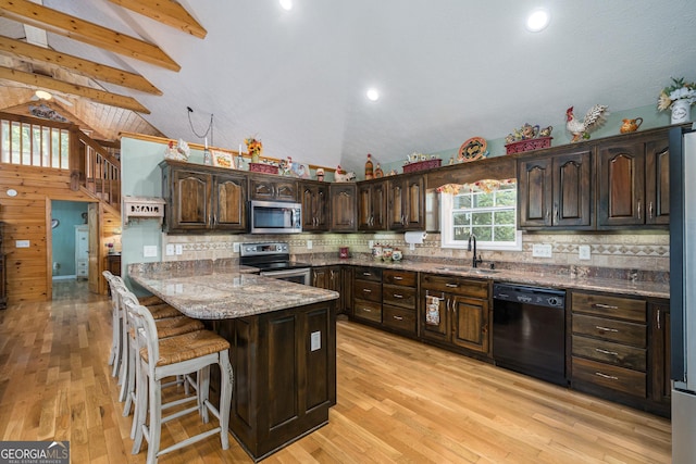 kitchen featuring a peninsula, a sink, stainless steel appliances, dark brown cabinetry, and light wood-type flooring