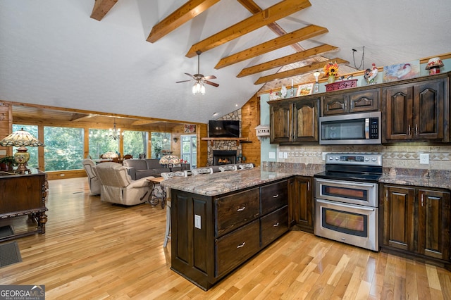 kitchen with beamed ceiling, open floor plan, dark brown cabinetry, appliances with stainless steel finishes, and light wood finished floors