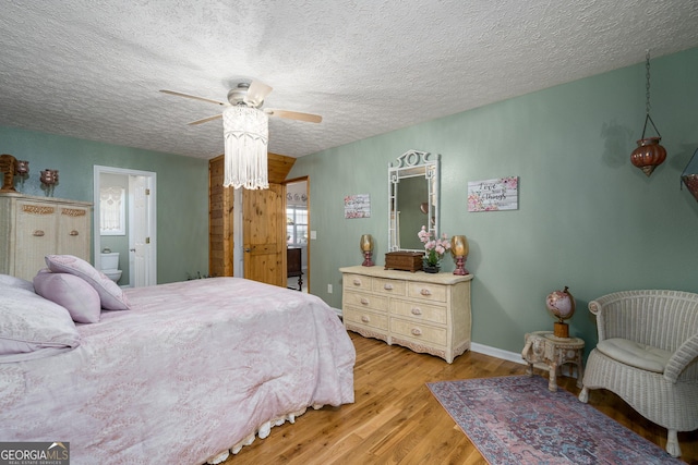 bedroom featuring a ceiling fan, a textured ceiling, ensuite bath, light wood finished floors, and baseboards