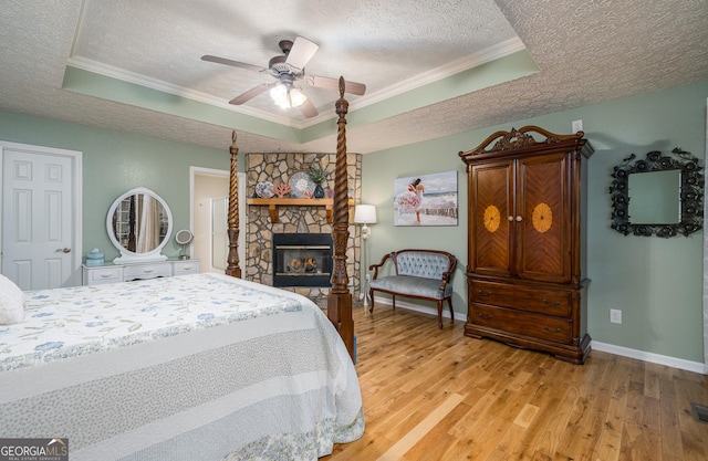 bedroom with a raised ceiling, ornamental molding, light wood-type flooring, and a textured ceiling