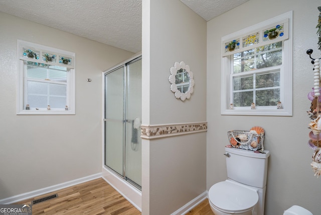 bathroom with a wealth of natural light, a shower stall, and wood finished floors