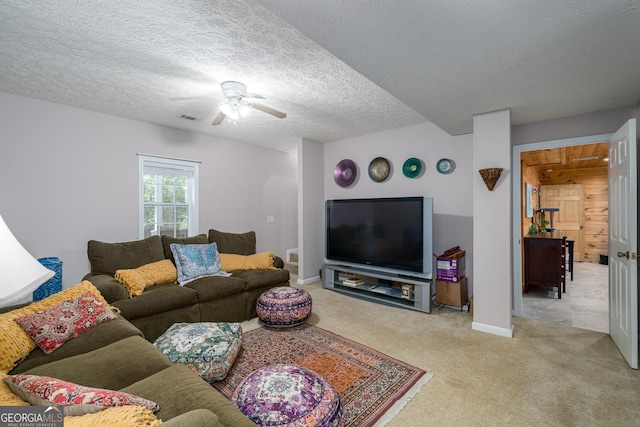 living area with visible vents, baseboards, ceiling fan, carpet, and a textured ceiling