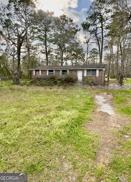 ranch-style house featuring dirt driveway and a front lawn