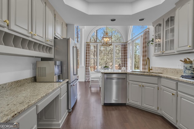 kitchen with glass insert cabinets, dishwasher, light stone counters, dark wood-style floors, and a sink