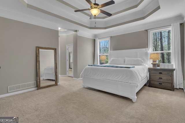 bedroom featuring a tray ceiling, visible vents, light colored carpet, and ornamental molding