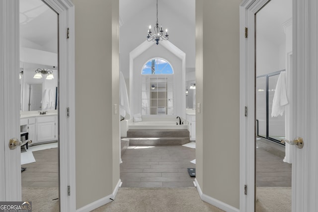 hallway featuring wood finished floors, baseboards, carpet floors, and a chandelier